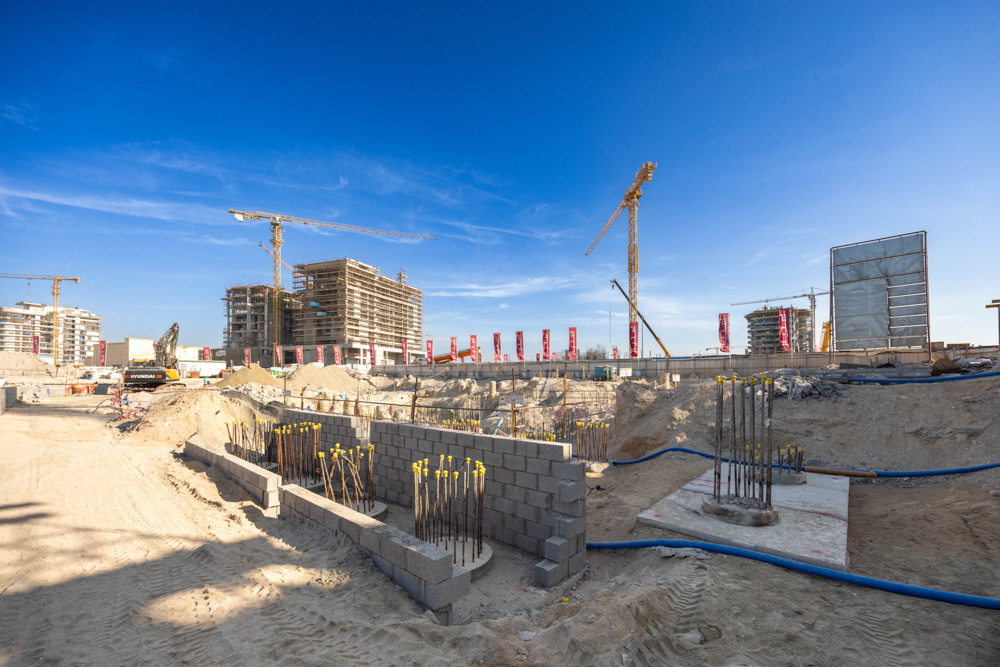 Cotier House 2 By Imtiaz Construction site with cranes, new buildings, and exposed foundations under a clear blue sky.